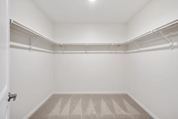 a walkin closet with white walls and carpet
