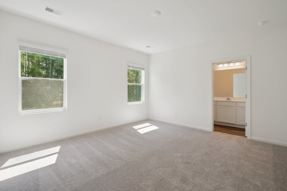 an empty bedroom with two windows  and carpets