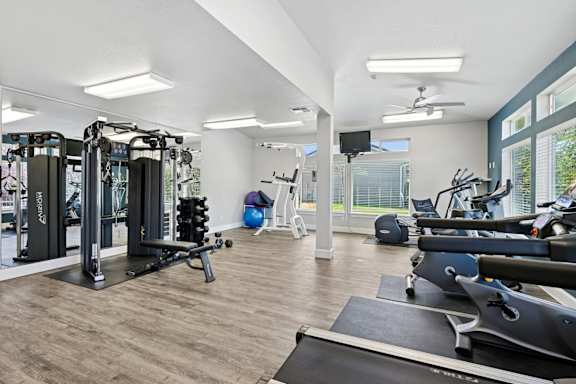 A spacious gym with a variety of equipment including treadmills, weights, and exercise machines at The Madison apartments in Olympia, WA