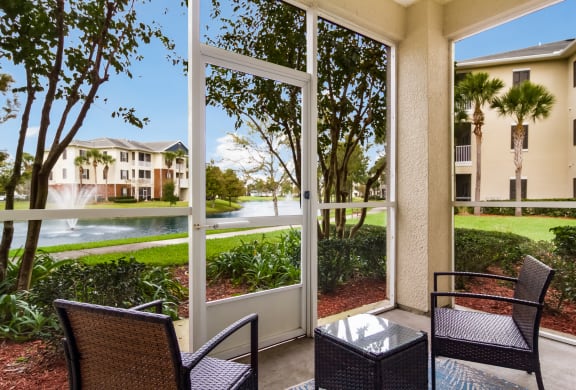 Screened patio with outdoor chairs in Wynnfield Lakes apartments in Jacksonville, FL