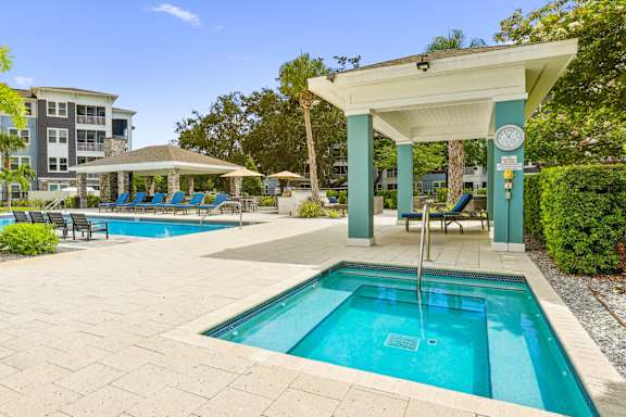 Jacuzzi with shaded seating area by the pool at Dunedin Commons apartments in Dunedin, FL