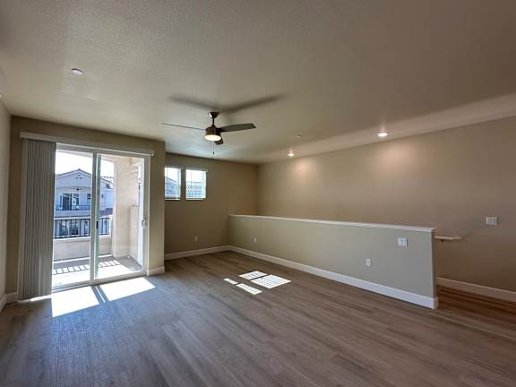 A room with a ceiling fan and sliding glass doors.