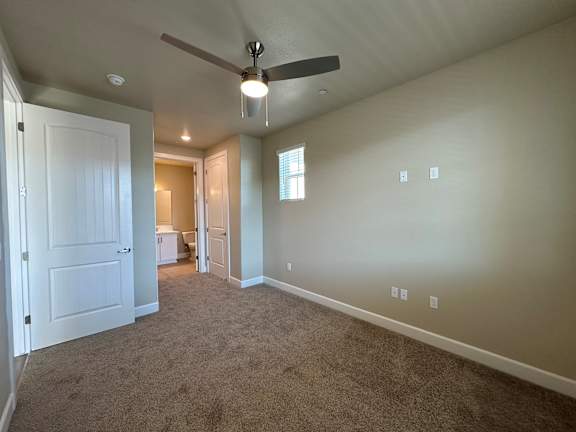 A room with a ceiling fan and carpeted floor.