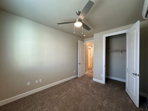 A room with a ceiling fan and carpeted floor.