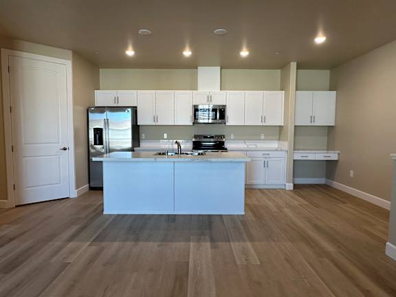 A kitchen with white cabinets and a wooden floor.