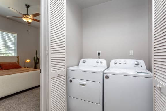 a bedroom with a ceiling fan and a washer and dryer