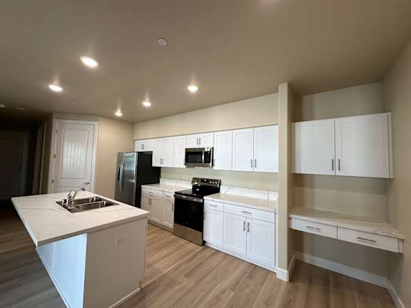 A kitchen with white cabinets and a wooden floor.