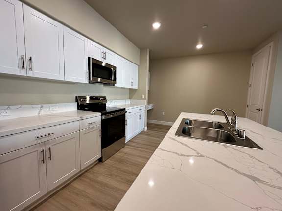 A kitchen with white cabinets and a marble countertop.