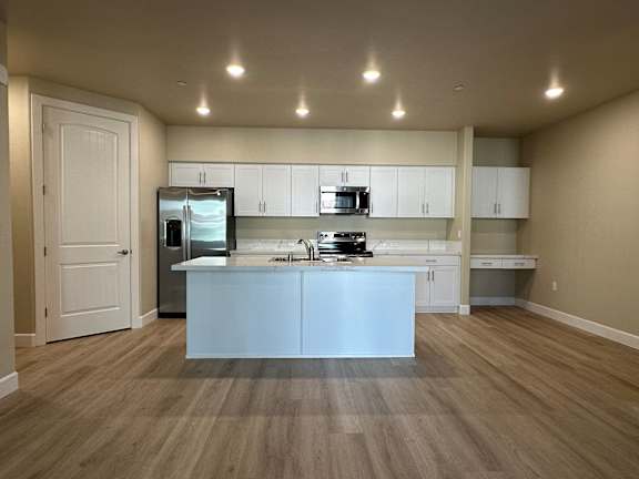 A kitchen with white cabinets and a wooden floor.