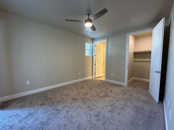 A room with a ceiling fan and carpeted floor.