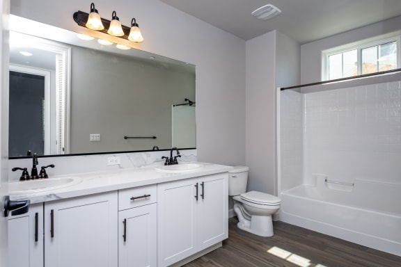 a bathroom with white cabinets and a white toilet next to a white bathtub