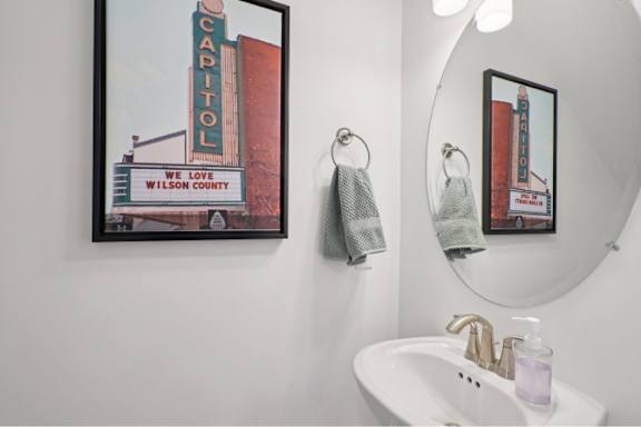 A bathroom with a white sink and a mirror with a picture of a capitol building on it.
