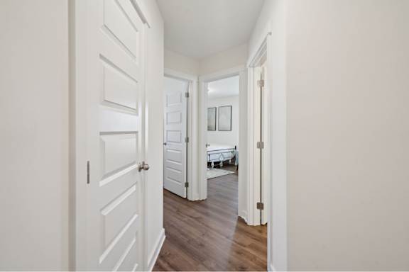 A hallway with a white door and a white wall.