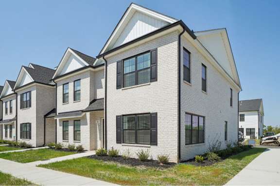 A white house with black shutters and a grey roof.