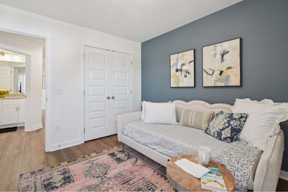 A living room with a grey couch and two abstract paintings on the wall.