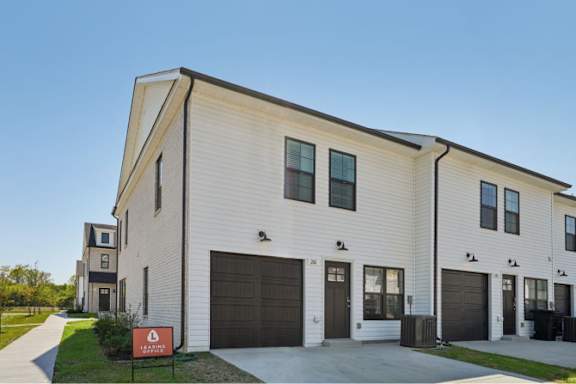 A modern two-story house with a garage and a red sign in front.