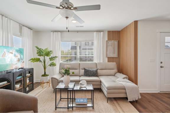 A living room with a large couch, a coffee table, and a ceiling fan.