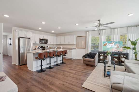 A modern kitchen with white cabinets and a wooden floor.