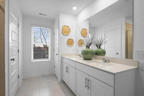 A bathroom with white cabinets and a large mirror.
