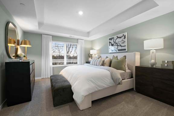 A bedroom with a large bed, a dresser, and a mirror.