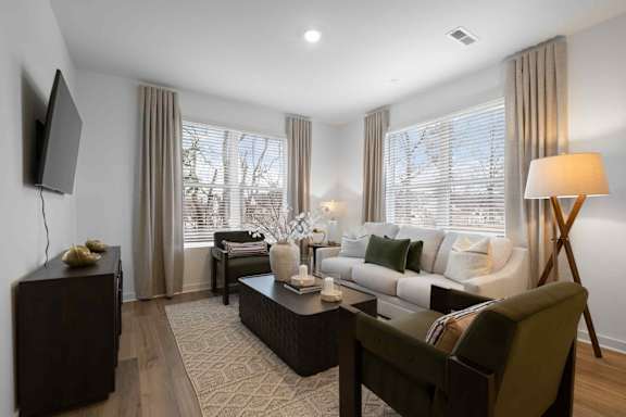 A modern living room with a dark brown sofa, a wooden coffee table, and a flat-screen TV mounted on the wall.