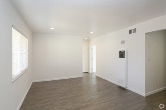 an empty living room with white walls and a wood floor