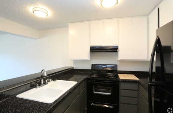 a kitchen with white cabinets and black countertops
