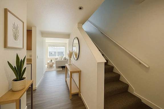 A hallway with a staircase and a mirror on the wall.