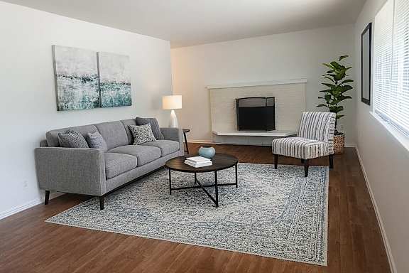 A living room with a grey couch, a coffee table, and a painting on the wall.