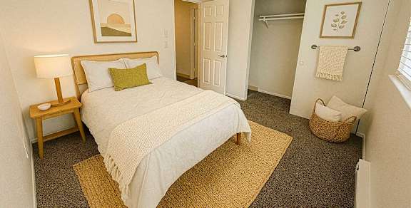 A bedroom with a bed, nightstand, and a basket on the floor.