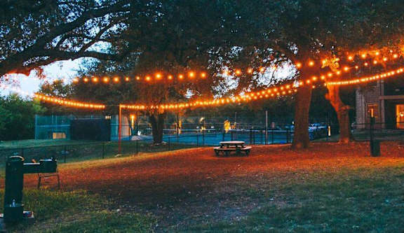 Outdoor gathering area with string lights at dusk at Skyline at Barton Creek Apartments, Texas, 78758