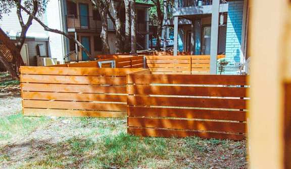 Wooden privacy fence with tree shade at Skyline at Barton Creek Apartments, Austin