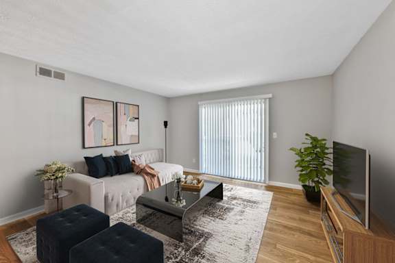 A living room with a white couch, a coffee table, and a television.
