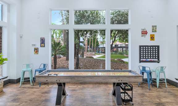 a pool table in a room with windows and a view of a park at Montage at Pecos Ranch Apartments, Arizona, 85286
