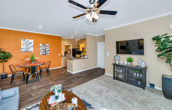 the living room and dining area of a home with a ceiling fan and a tv at Montage at Pecos Ranch Apartments, Arizona, 85286