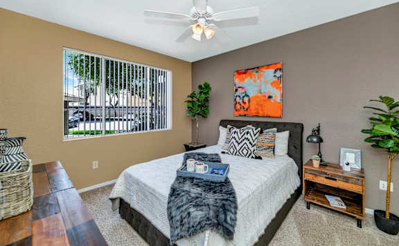 the master bedroom has a large window and a ceiling fan at Montage at Pecos Ranch Apartments, Arizona