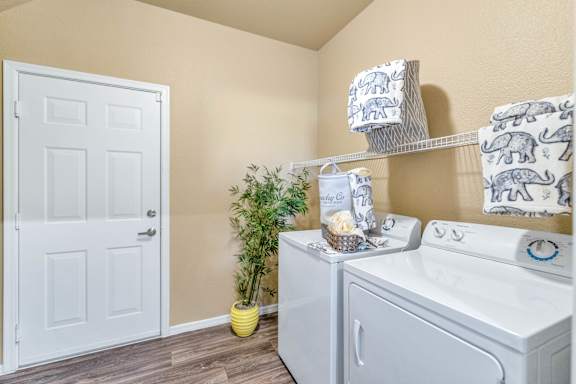 the washer and dryer in a laundry room with a white door at Montage at Pecos Ranch Apartments, Chandler, AZ