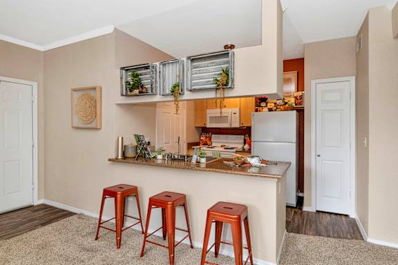 a kitchen with a bar and three stools at Montage at Pecos Ranch Apartments, Arizona, 85286