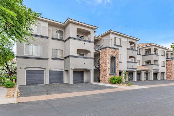 a street view of an apartment building with garage doors at Montage at Pecos Ranch Apartments, Chandler, Arizona