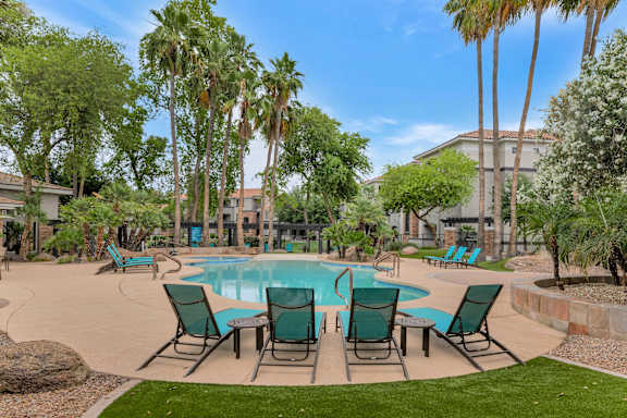 a swimming pool with patio furniture and palm trees at Montage at Pecos Ranch Apartments, Chandler, Arizona