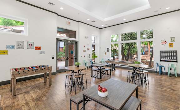 a common room with tables and chairs and a large window at Montage at Pecos Ranch Apartments, Arizona