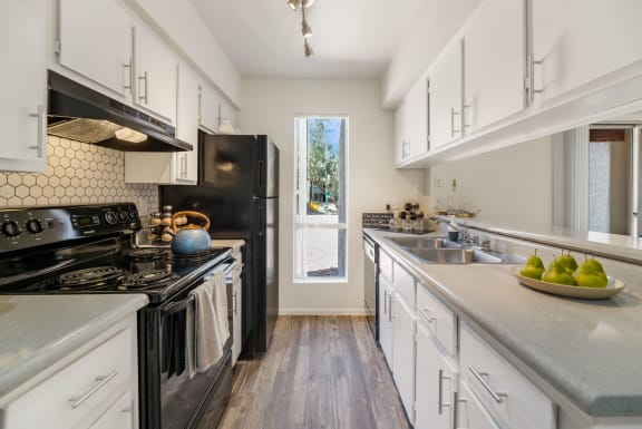 a kitchen with white cabinets and black appliances and a window at Glen Brae, Arizona, 85301