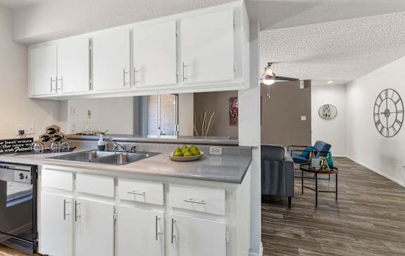 A modern kitchen with white cabinets and a wooden floor.