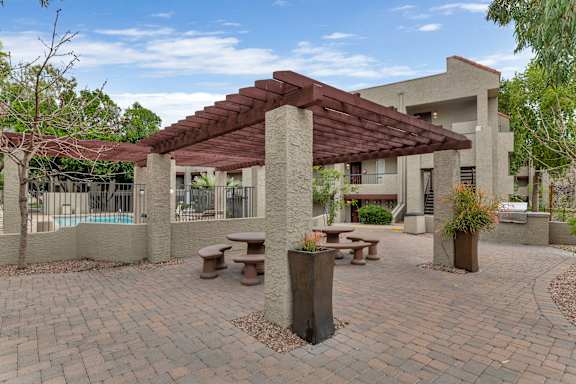 A patio area with a table and chairs under a pergola.