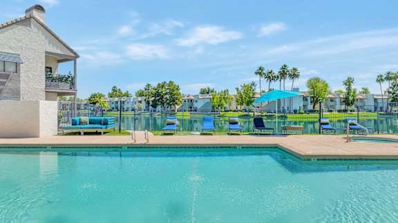 A swimming pool with a building and palm trees in the background.