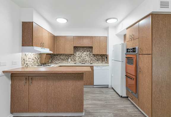 A kitchen with wooden cabinets and a white dishwasher at The Phoenix Apartments on 6th Avenue, Arizona