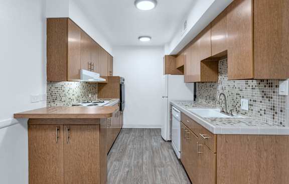 A kitchen with wooden cabinets and a tiled backsplash at The Phoenix Apartments on 6th Avenue, Phoenix