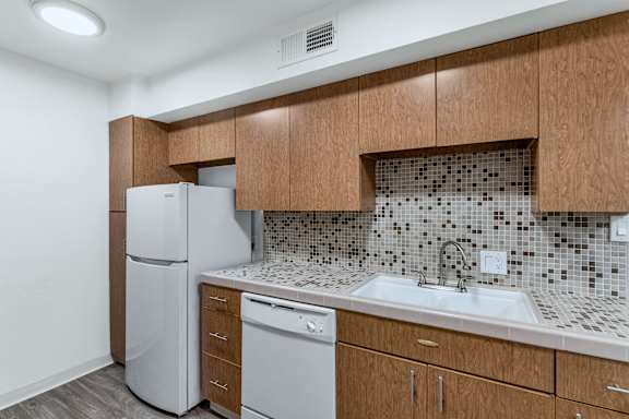 A kitchen with a white fridge and a white dishwasher at The Phoenix Apartments on 6th Avenue, Phoenix, AZ