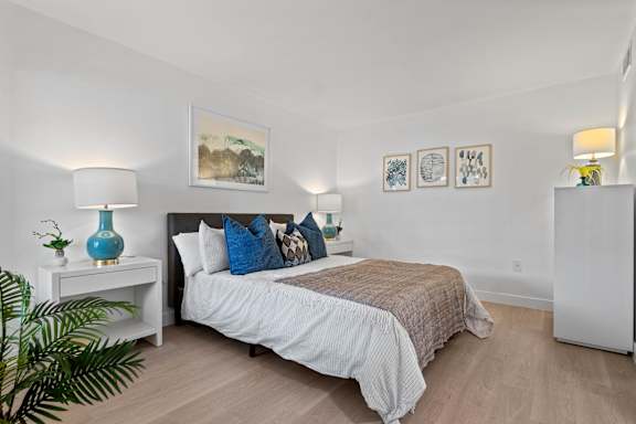 A bedroom with a bed, nightstands, and a plant.