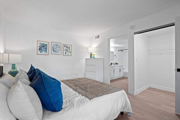 A bedroom with a bed, pillows, and pictures on the wall.